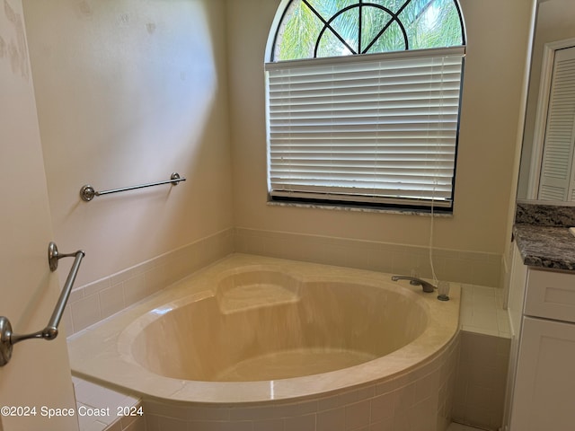 bathroom featuring tiled tub and vanity