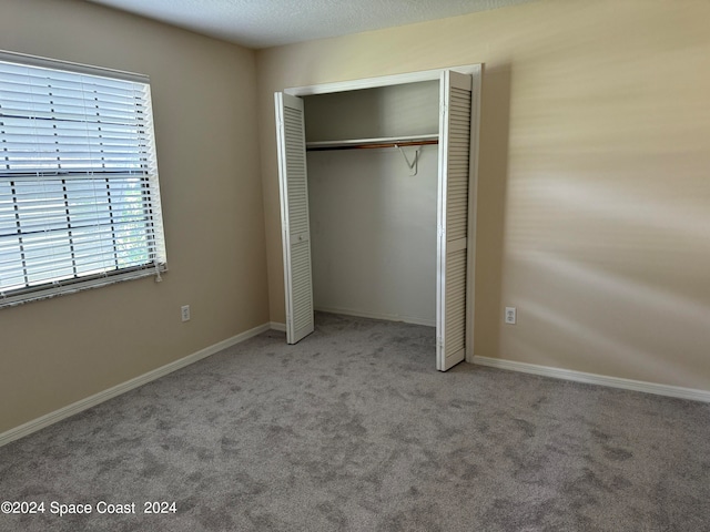 unfurnished bedroom featuring carpet floors, a textured ceiling, and a closet