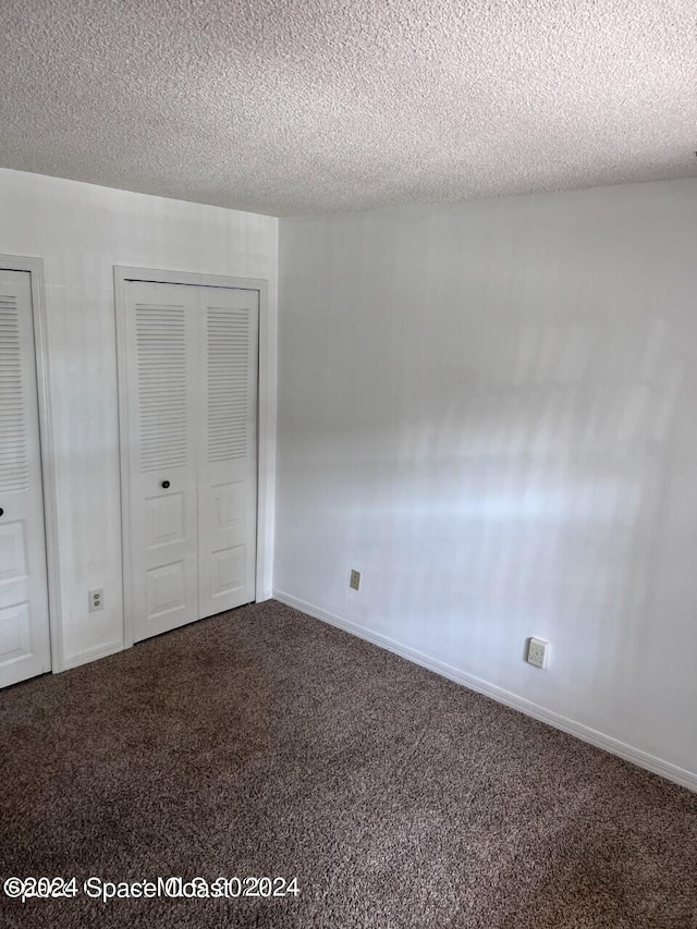 empty room featuring dark carpet and a textured ceiling