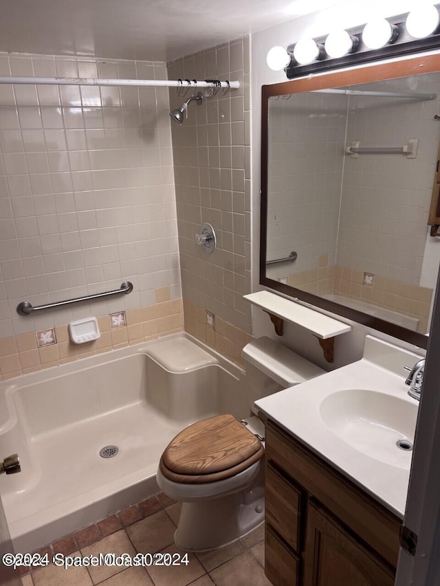 bathroom with a tile shower, vanity, tile patterned flooring, and toilet