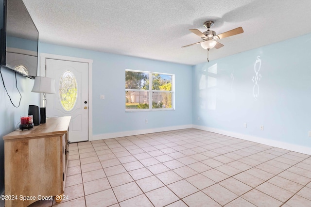 entryway featuring ceiling fan, light tile patterned flooring, and a textured ceiling