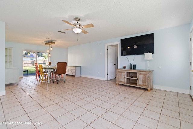 tiled dining space with ceiling fan and a textured ceiling