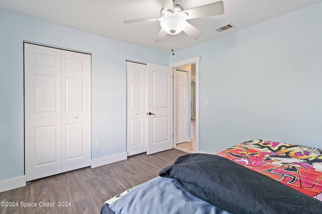 bedroom featuring light hardwood / wood-style floors, two closets, and ceiling fan