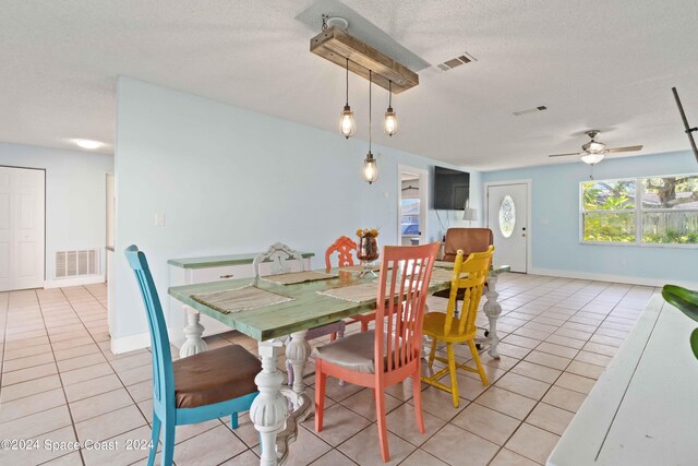 dining space featuring ceiling fan, light tile patterned flooring, and a textured ceiling