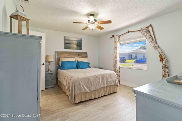 bedroom featuring a textured ceiling, ceiling fan, and light hardwood / wood-style flooring