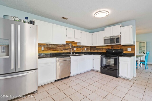 kitchen featuring light tile patterned floors, sink, white cabinetry, stainless steel appliances, and decorative backsplash