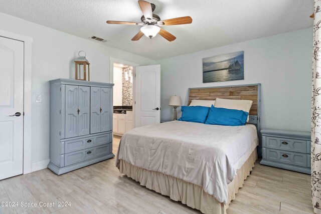 bedroom with ensuite bath, ceiling fan, light hardwood / wood-style floors, and a textured ceiling