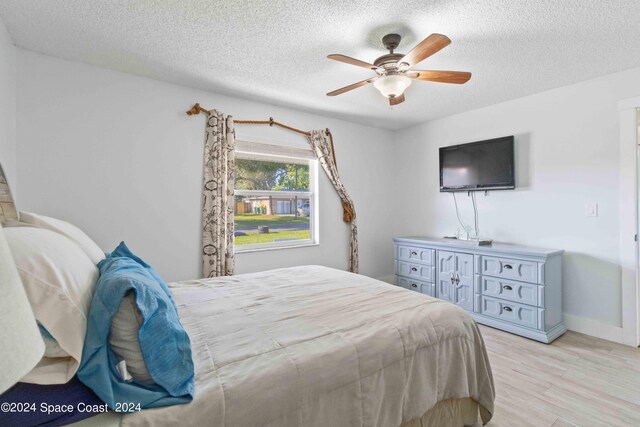 bedroom with a textured ceiling, light hardwood / wood-style floors, and ceiling fan