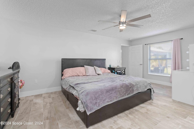 bedroom with ceiling fan, light hardwood / wood-style floors, and a textured ceiling