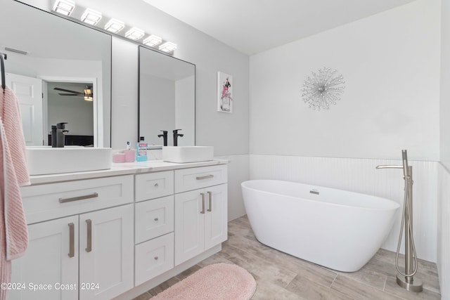 bathroom featuring a tub to relax in, ceiling fan, and vanity