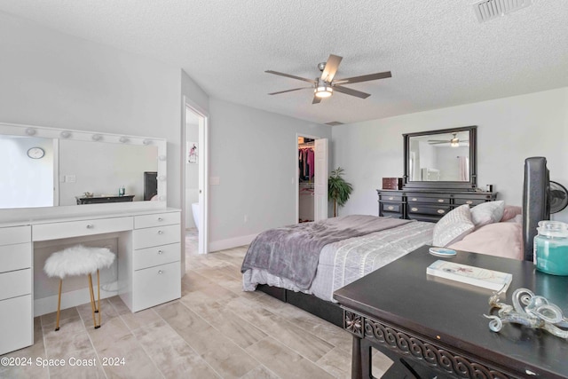 bedroom with a walk in closet, ceiling fan, a closet, and a textured ceiling