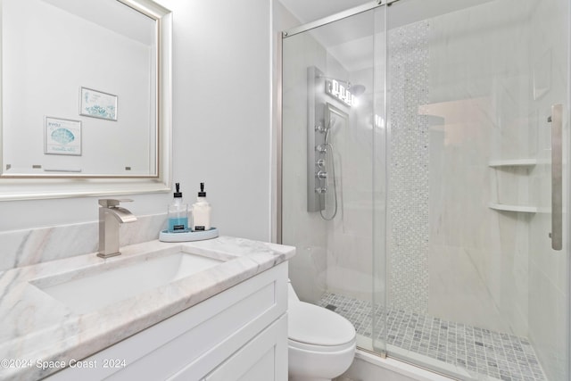 bathroom featuring vanity, toilet, and a shower with shower door