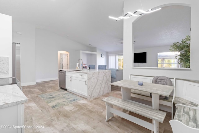 dining room featuring ceiling fan, sink, vaulted ceiling, and light wood-type flooring