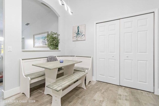 dining area featuring light hardwood / wood-style flooring, breakfast area, and lofted ceiling