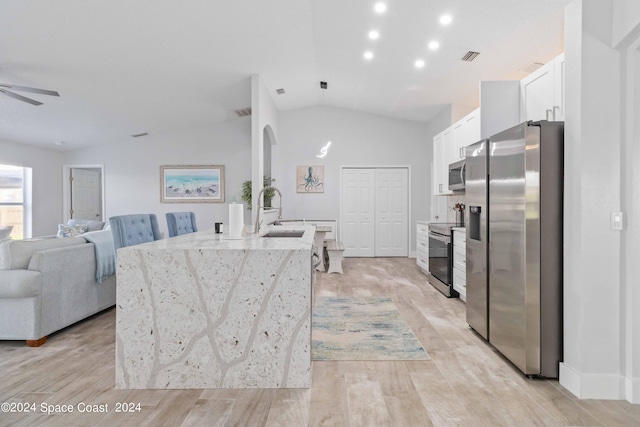 kitchen featuring sink, light hardwood / wood-style floors, lofted ceiling, white cabinets, and appliances with stainless steel finishes