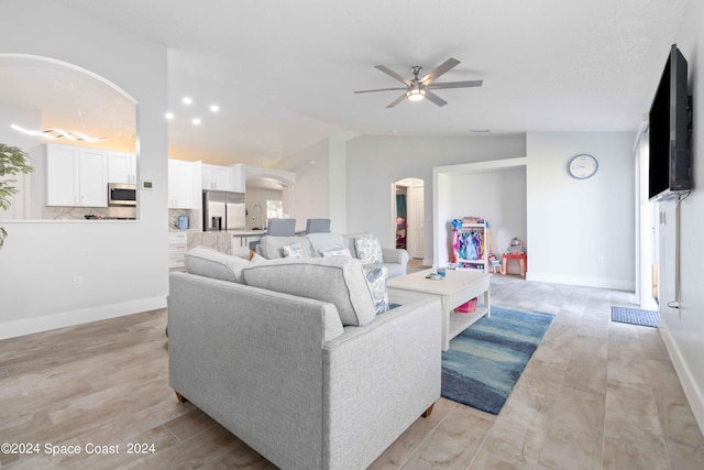 living room featuring ceiling fan, light hardwood / wood-style floors, and vaulted ceiling