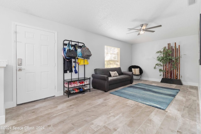 living area featuring ceiling fan, light hardwood / wood-style flooring, and a textured ceiling