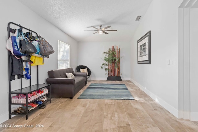 living room with ceiling fan, a textured ceiling, and light hardwood / wood-style flooring