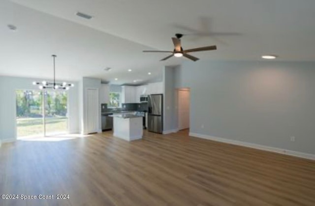 interior space featuring hardwood / wood-style flooring, ceiling fan with notable chandelier, and lofted ceiling