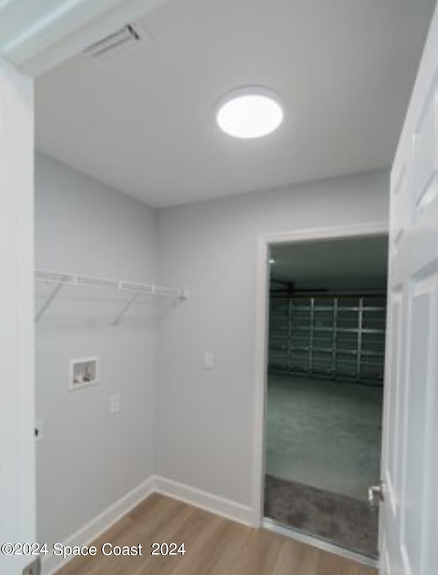 clothes washing area with washer hookup and light hardwood / wood-style flooring