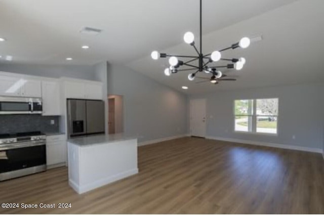 kitchen with white cabinetry, hardwood / wood-style flooring, appliances with stainless steel finishes, an inviting chandelier, and vaulted ceiling