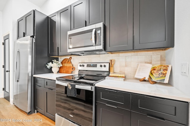 kitchen featuring appliances with stainless steel finishes, light hardwood / wood-style flooring, and decorative backsplash