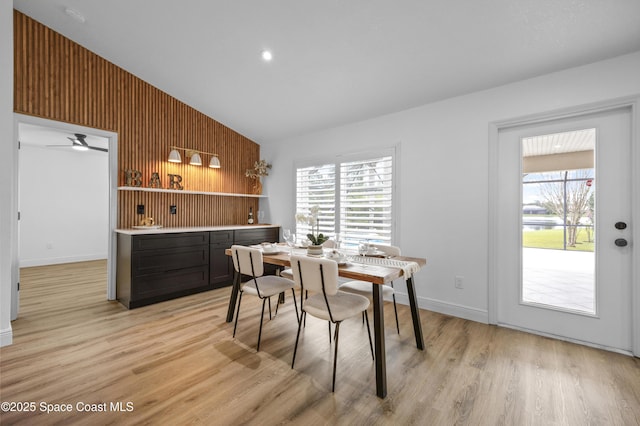 dining room featuring a wealth of natural light, light hardwood / wood-style floors, and wood walls