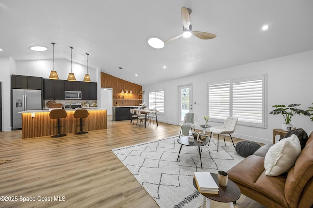 living room with lofted ceiling, ceiling fan, and light wood-type flooring