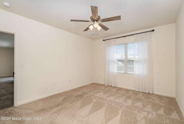 spare room featuring ceiling fan and light carpet