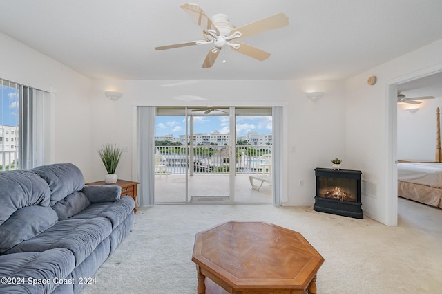 carpeted living room with a fireplace, ceiling fan, and plenty of natural light