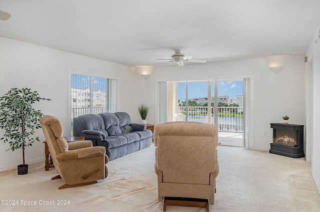 8931 Lake Dr Unit 401, Cape Canaveral, FL 32920 - living area featuring plenty of natural light, a warm lit fireplace, light carpet, and a ceiling fan