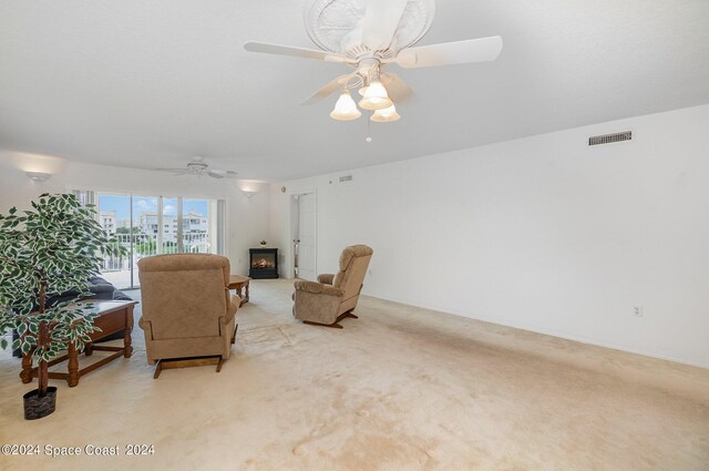 sitting room featuring ceiling fan, a fireplace, and light carpet