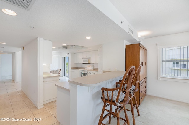 8931 Lake Dr Unit 401, Cape Canaveral, FL 32920 - kitchen with light countertops, visible vents, a peninsula, white appliances, and a kitchen bar