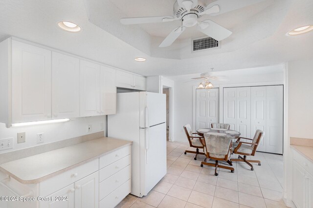 kitchen with ceiling fan, light tile patterned flooring, white fridge, and white cabinetry