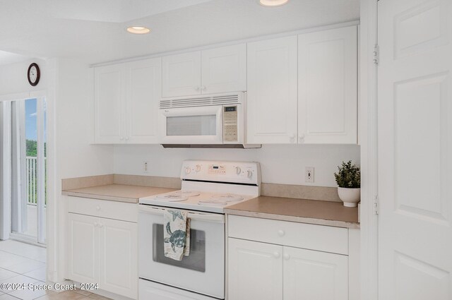 kitchen with white appliances, white cabinetry, and light tile patterned flooring