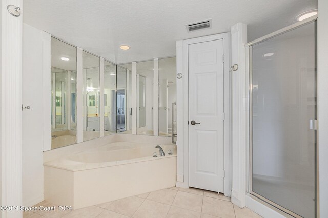 bathroom featuring shower with separate bathtub, a textured ceiling, and tile patterned floors