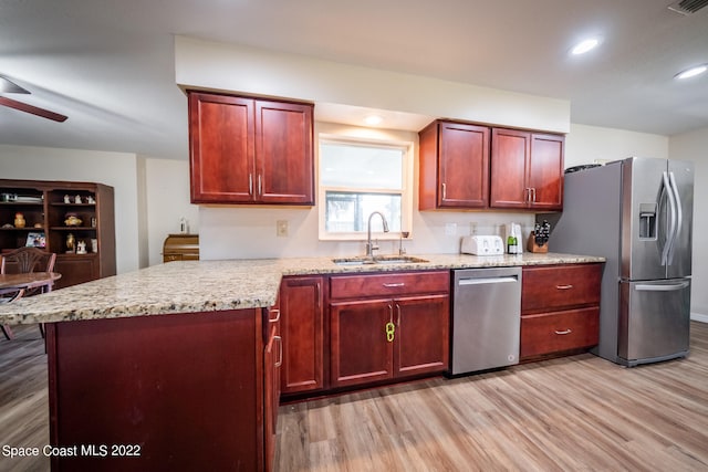 kitchen with appliances with stainless steel finishes, sink, ceiling fan, and light hardwood / wood-style flooring