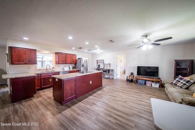 kitchen featuring ceiling fan, hardwood / wood-style flooring, light stone countertops, and a center island