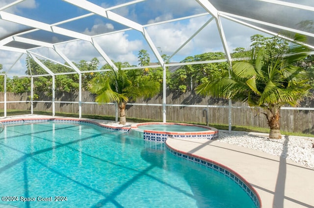 view of swimming pool featuring glass enclosure, an in ground hot tub, and a patio