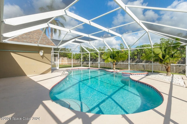 view of pool with glass enclosure, an in ground hot tub, and a patio area