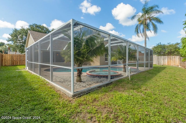 back of house featuring a lawn, glass enclosure, and a swimming pool with hot tub