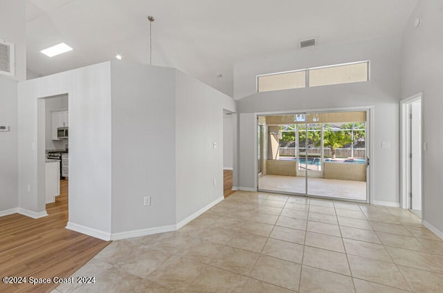 empty room with light tile patterned floors and high vaulted ceiling