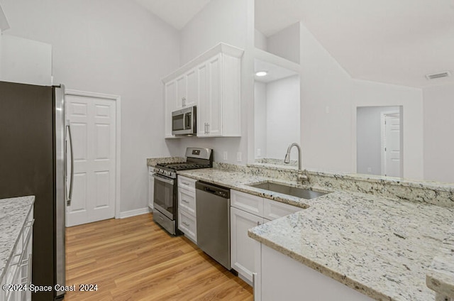 kitchen with light wood-type flooring, sink, white cabinetry, stainless steel appliances, and light stone countertops