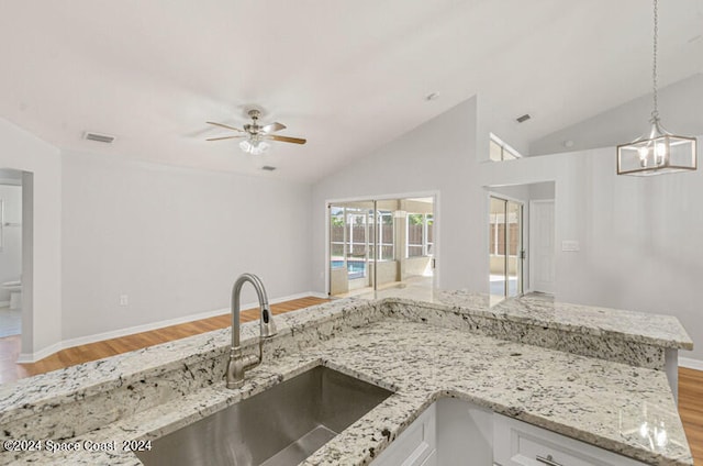 kitchen featuring ceiling fan with notable chandelier, light wood-type flooring, vaulted ceiling, and sink