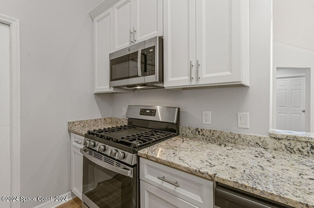 kitchen with wood-type flooring, light stone countertops, stainless steel appliances, and white cabinets