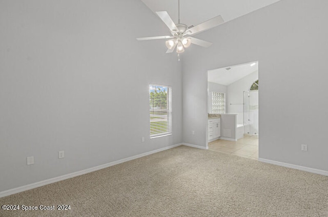 carpeted empty room with ceiling fan and high vaulted ceiling