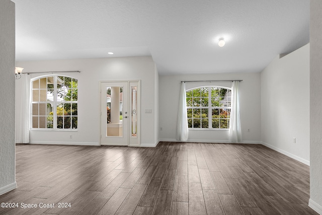 interior space featuring a textured ceiling, a healthy amount of sunlight, and dark hardwood / wood-style flooring