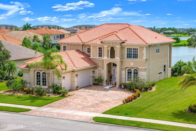 mediterranean / spanish house with a front yard, a garage, and a water view