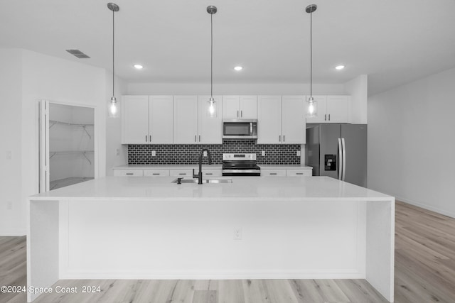 kitchen featuring a sink, a large island with sink, visible vents, white cabinets, and appliances with stainless steel finishes