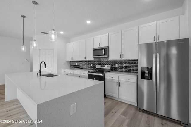 kitchen featuring a sink, stainless steel appliances, light wood-type flooring, an island with sink, and white cabinets